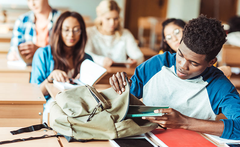 student packing school notebooks into backpack