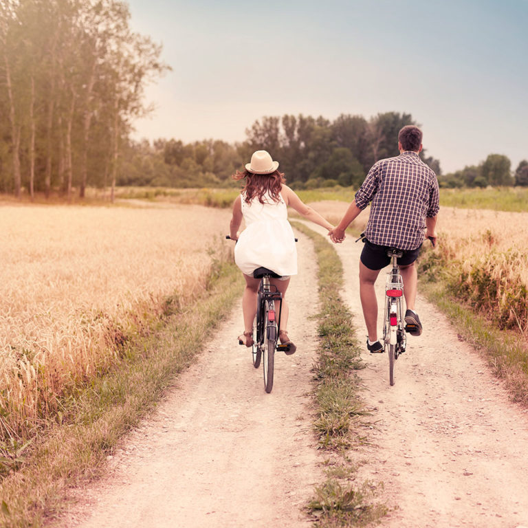 Couple biking together on a dirt path